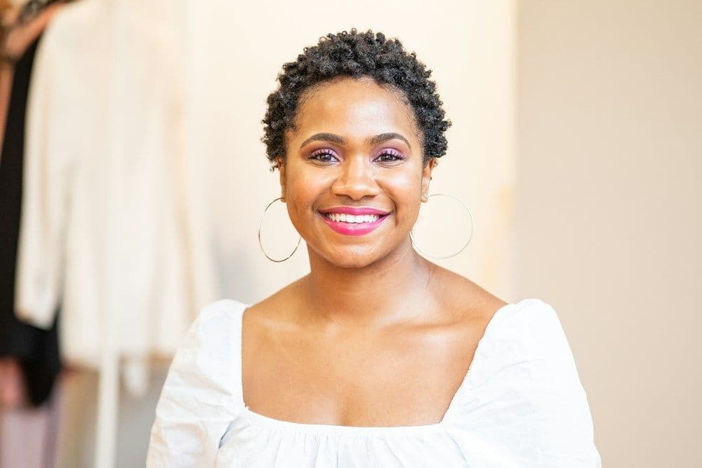 A smiling woman with curly hair in a bright room